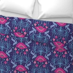 a bed with blue and red floral print on the comforter, along with two pillows