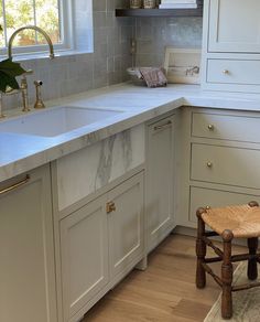 a kitchen with white cabinets and marble counter tops