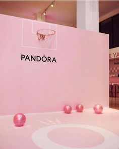 pink balls are on the floor in front of a wall that says pandara and is decorated with a basketball hoop