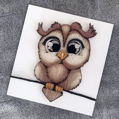 an embroidered owl sitting on top of a white piece of paper with a black eye