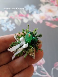 someone is holding a small green bird brooch