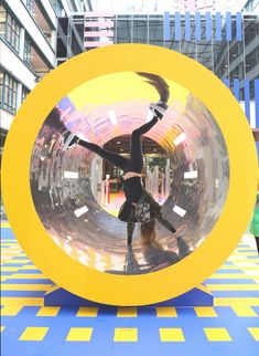 a woman standing in front of a giant mirror ball with her arms out and legs spread wide