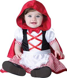 a baby dressed up as a little red riding hoodie and dress, sitting on the floor