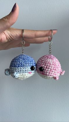 two small crocheted keychains are being held by a hand