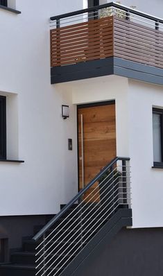 a white house with black railing and wooden door