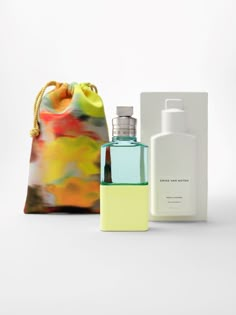 two bottles and a bag sitting next to each other on a white surface with an object in the background