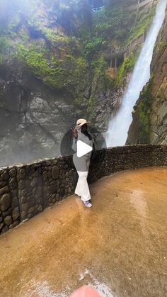 a person standing on the edge of a cliff looking at a waterfall in the distance