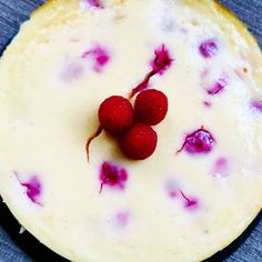 two raspberries sit on top of a cheesecake