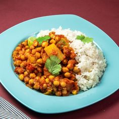 a blue plate topped with rice and chickpeas on top of a red table