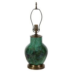 a green vase sitting on top of a table next to a metal light fixture with a wire