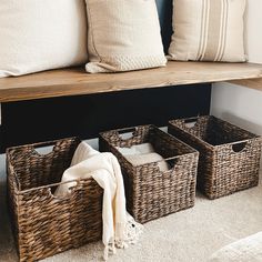 three wicker baskets under a bench with white pillows