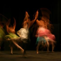 blurry photograph of people dancing on the floor in front of a black background,