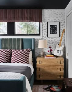 a bed room with a neatly made bed and a guitar on top of the dresser