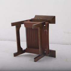 a small wooden chair sitting on top of a white floor next to a brown trash can