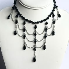 Unveil your dark, elegant side with this 16" dramatic black Gothic romance choker. This striking, one-of-a-kind piece features faceted black crystals and three rows of swagged silver chain, each adorned with teardrop crystals and faceted rondelles for a luxurious finish. The choker fastens securely with a lobster clasp closure, but if you'd like it to hang longer, just message me for custom chain adjustments. Perfect for adding a bold, Gothic touch to any outfit. Wedding Jewelery, Custom Chain, Gothic Romance, Romantic Goth, Silver Chains, Accessories Jewelry Earrings, Beads And Wire, Faceted Crystal