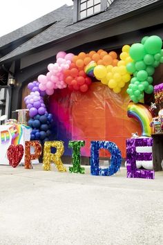 there are balloons and letters that spell out the word pride in front of a building