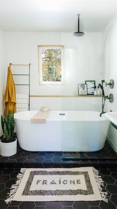 a white bath tub sitting next to a sink under a mirror in a bathroom with black and white tile flooring