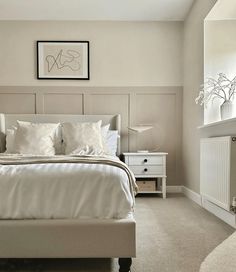 a white bed sitting next to a window in a bedroom on top of a carpeted floor