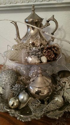 a silver tea pot filled with ornaments on top of a table