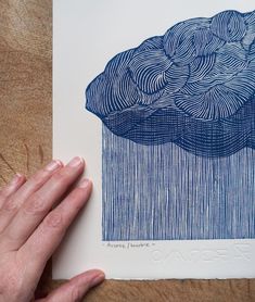 a hand is holding up a blue and white paper with an image of a cloud on it