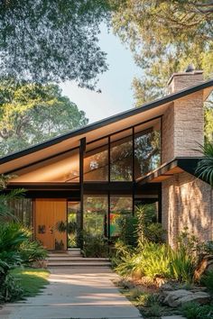 a modern house in the woods with lots of trees and plants on either side of it