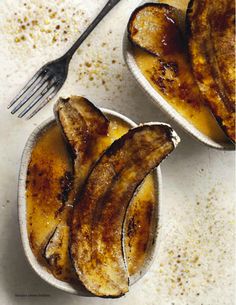 two bowls filled with bananas sitting on top of a white counter next to a fork