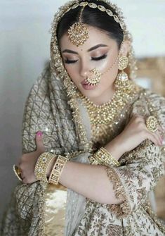 a woman in a bridal outfit with jewelry on her head and hands around her neck