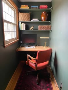 a desk with a computer on top of it in front of a window and bookshelves