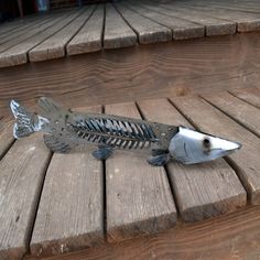 a metal fish sitting on top of a wooden deck