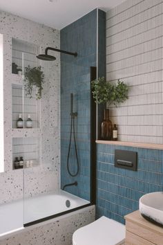 a blue tiled bathroom with a white toilet and bathtub next to a shower stall