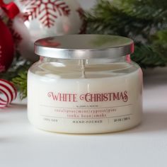 a white candle sitting on top of a table next to christmas decorations and baubles