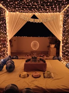 a table topped with cake and balloons under a canopy covered in white draping