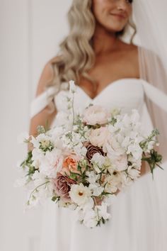 a bride holding a bouquet of white and pink flowers