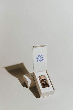 an open box with a ring in it on a white surface and the lid opened