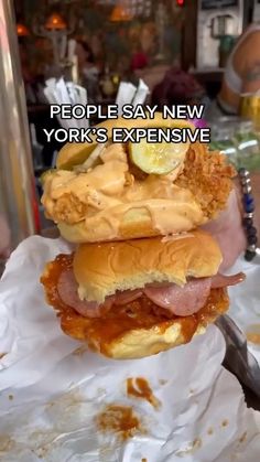 a person holding a large sandwich in their hand with the caption people say new york's expensive