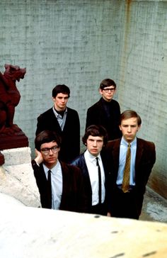 a group of young men standing next to each other in front of a wall with a statue behind them