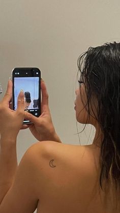 a woman is taking a selfie in the mirror with her cell phone while brushing her hair