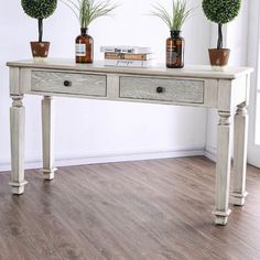 three potted plants sit on top of a white table in front of a wall