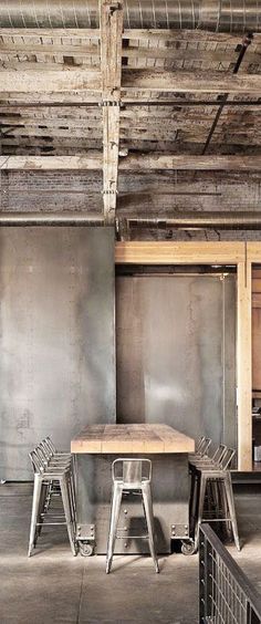 an empty table and chairs in a room with metal partitions on the wall behind it