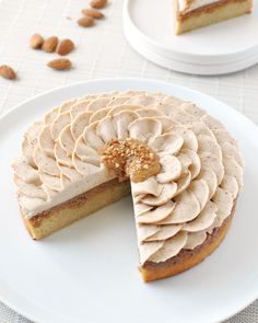 a white plate topped with a cake covered in frosting next to a slice cut out