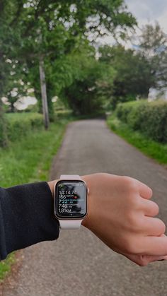 a person wearing an apple watch on their wrist with trees and grass in the background