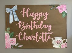 a happy birthday chocolate sign with pink flowers and teapots on it's side