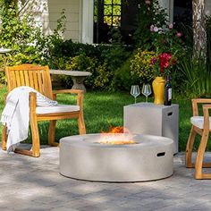 a fire pit sitting on top of a brick patio next to two chairs and a table