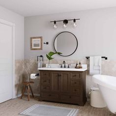 a white bath tub sitting next to a bathroom sink under a round mirror on a wall