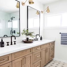 a bathroom with two sinks, mirrors and lights on the wall above them is shown