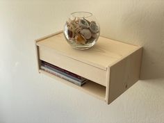 a glass bowl filled with shells on top of a wooden shelf