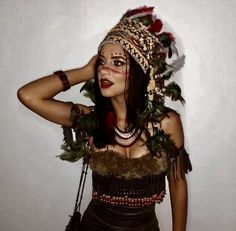 a woman with makeup on her face and feathers around her head, wearing a costume