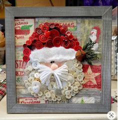 a christmas card with buttons and a santa clause hat on it, in a frame