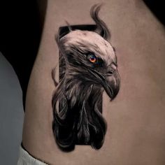 an eagle tattoo on the side of a woman's thigh, with red eyes