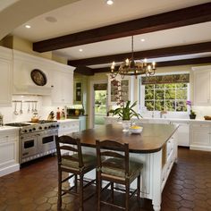 a large kitchen with white cabinets and wooden flooring, along with an island in the middle